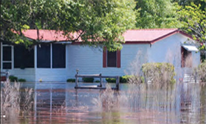 A home with flood damage and the flood waters up to the door
