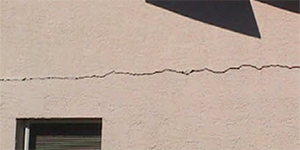 A close up of a large crack in a cememnt block home
